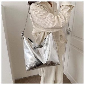 Model wearing a large capacity silver metallic shoulder tote bag in minimalist interior