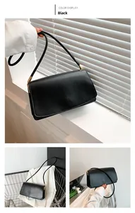 Detail view of minimalist black PU leather baguette bag with gold metal buckle