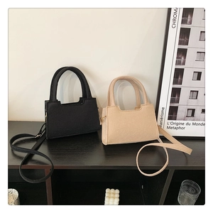 Detail of mini felt tote bags in black and beige with U-shaped cutout and shoulder straps
