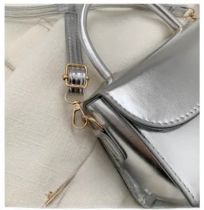 Detailed close-up of glossy silver handbag featuring a shiny gold metal swivel hook