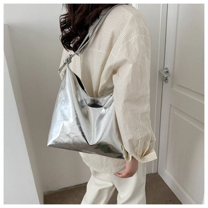 Detail of a large silver metallic hobo bag with slim shoulder strap shown on model