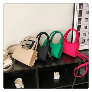Group shot of felt crossbody bags in beige, black, green, and rose red colors on a wooden shelf