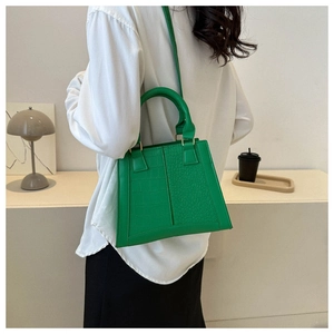 Detail of bright green crocodile pattern handbag with dual handles and long strap