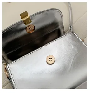 Detail shot of the vintage gold magnetic snap closure on a silver crossbody bag
