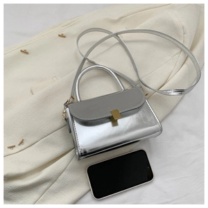 Detailed macro view showing the mini silver crossbody bag size compared to a smartphone
