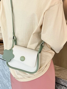 Minimalist beige small square bag with green trim and floral charm shown on model