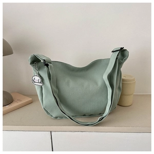 Close-up of light green corduroy moon bag featuring a cute white dog charm detail