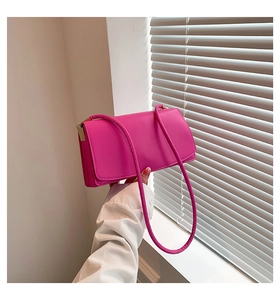Close-up of fuchsia minimalist rectangle handbag with sleek leather texture and metal buckle