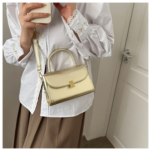 Detail of champagne gold glossy crossbody bag showing compact rectangle design and metallic clasp