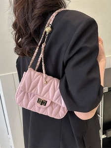 Pink quilted leather crossbody bag with gold chain strap worn by a model in a black suit