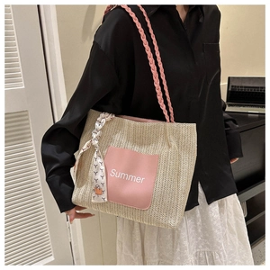 Detail der gewebten Strohtasche mit rosa Summer-Patch und dekorativem Seidenschal