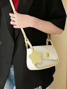 Minimalist beige crossbody square bag with yellow trim and flower pendant on a model