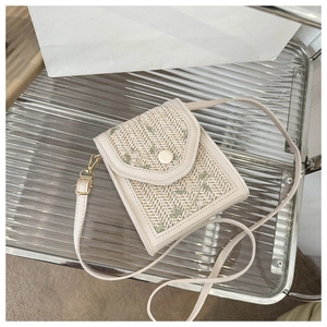 Detail of cream leather shoulder bag with floral embroidery and gold buckle hardware