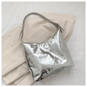 Detail of silver metallic hobo bag on beige blazer showing texture and adjustable strap