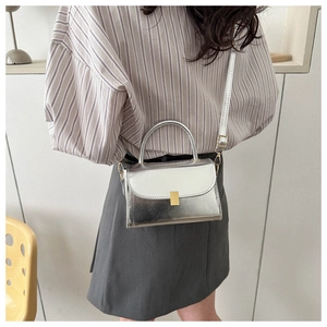 Silver metallic leather crossbody bag with top handle and gold clasp on a model
