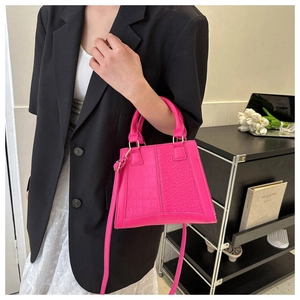 Detail of fuchsia trapezoid bag with crocodile and lizard texture on a model
