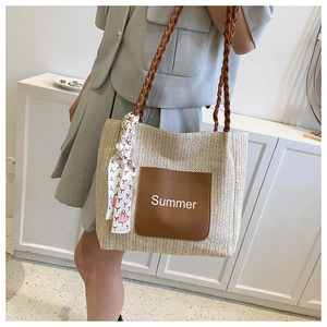Detail der Strohtasche mit Summer-Lederpatch und rot gemustertem Schal am Tragegriff