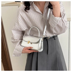 Detail of silver metallic mini crossbody bag with gold buckle on striped shirt outfit