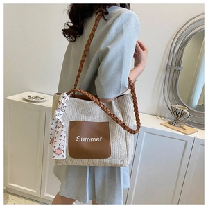 Detail der gewebten Strohtasche mit Ledertasche, Summer-Schriftzug und dekorativem Seidenschal