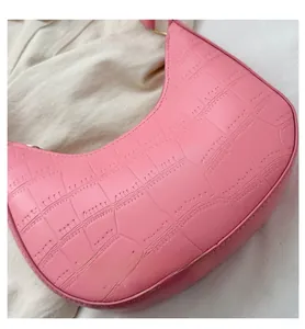Detail shot of pink crocodile pattern texture and gold hardware on the crescent bag