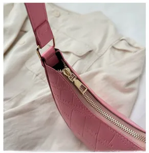 Detail of smooth gold-tone zipper and crocodile texture on pink underarm bag