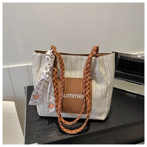 Detail der gewebten Strohtasche mit braunem Leder-Summer-Patch und Seidenschal-Griff