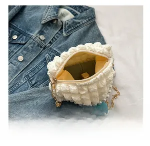 Detail showing white bubble texture tote bag with pearl chain and blue flower charm
