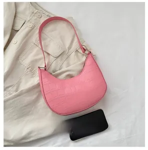 Pink crescent underarm bag with crocodile texture and phone for size comparison