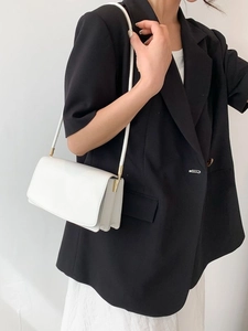 Minimalist white faux leather shoulder bag worn by model with gold hardware detail