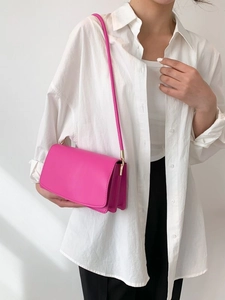 Minimalist bright pink crossbody flap bag with gold hardware and chic accordion structure