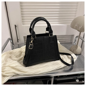 Detail of black faux leather bag with crocodile texture and gold hardware on a stylish cart