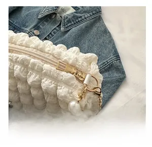 Close-up of white bubble pleated tote bag featuring pearl strap and golden chain detail