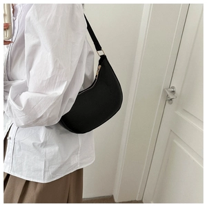 Side view of black crescent shoulder bag on model with minimalist white shirt styling