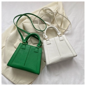 Detail view of stylish crocodile pattern small square bags in vibrant green and white colors