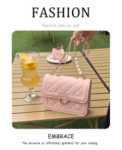 Pink quilted crossbody bag with pearl chain strap on a cafe table setting