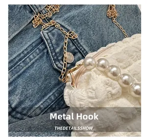 Detail showing the white bubble textured fabric with golden metal hook and pearl handle