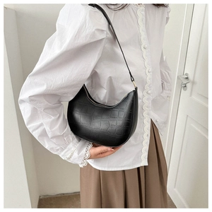 Detailed close-up of a black crocodile pattern crescent shoulder bag worn by a model