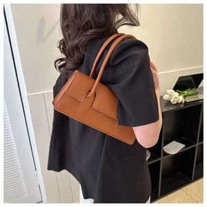 Caramel brown leather baguette bag styled as a shoulder underarm bag on a model