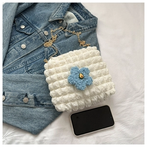 Detail of white bubble fabric bag with blue floral charm and gold metal chain strap