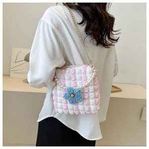 Detailed view of striped bubble fabric bag with floral charm and pearl strap on model