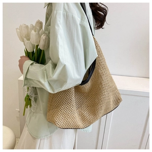 Detailed close-up of summer woven straw tote bag with black strap and mesh texture