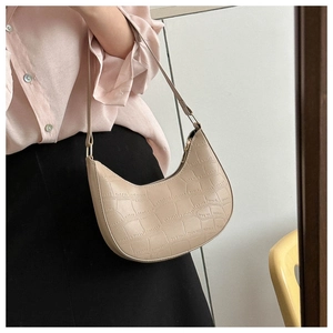 Detail of light beige croc-embossed hobo bag with gold hardware worn as a shoulder bag