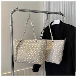 Dettaglio borse shopper intrecciate con ricamo a margherita e tracolla a catena