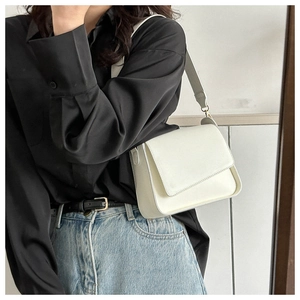 Dettaglio borsa a tracolla minimalista in pelle bianco crema indossata dalla modella