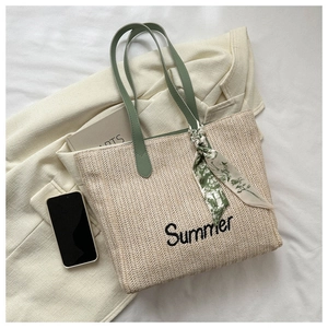 Détail du sac cabas en paille avec lanières en cuir vert, broderie Summer et foulard floral