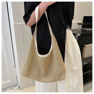 Detail of hollow woven straw hobo bag with cream leather trim and shoulder strap