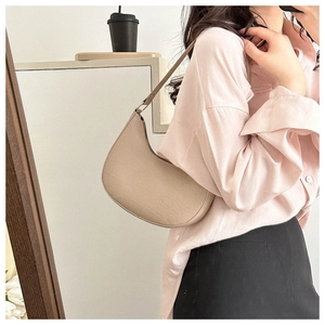 Detail of beige crescent underarm bag with crocodile pattern texture and sleek zipper