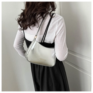 Close-up of silver metallic shoulder bag showing fashionable underarm wear and styling