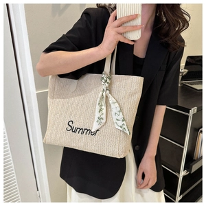 Détail d'un sac cabas en paille beige avec broderie Summer noire et foulard en soie floral