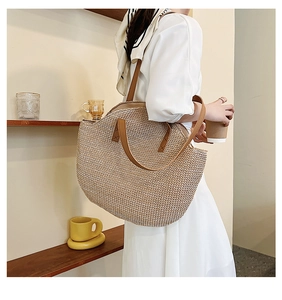 Detail of hand-woven straw tote bag with brown leather handles and natural fiber texture